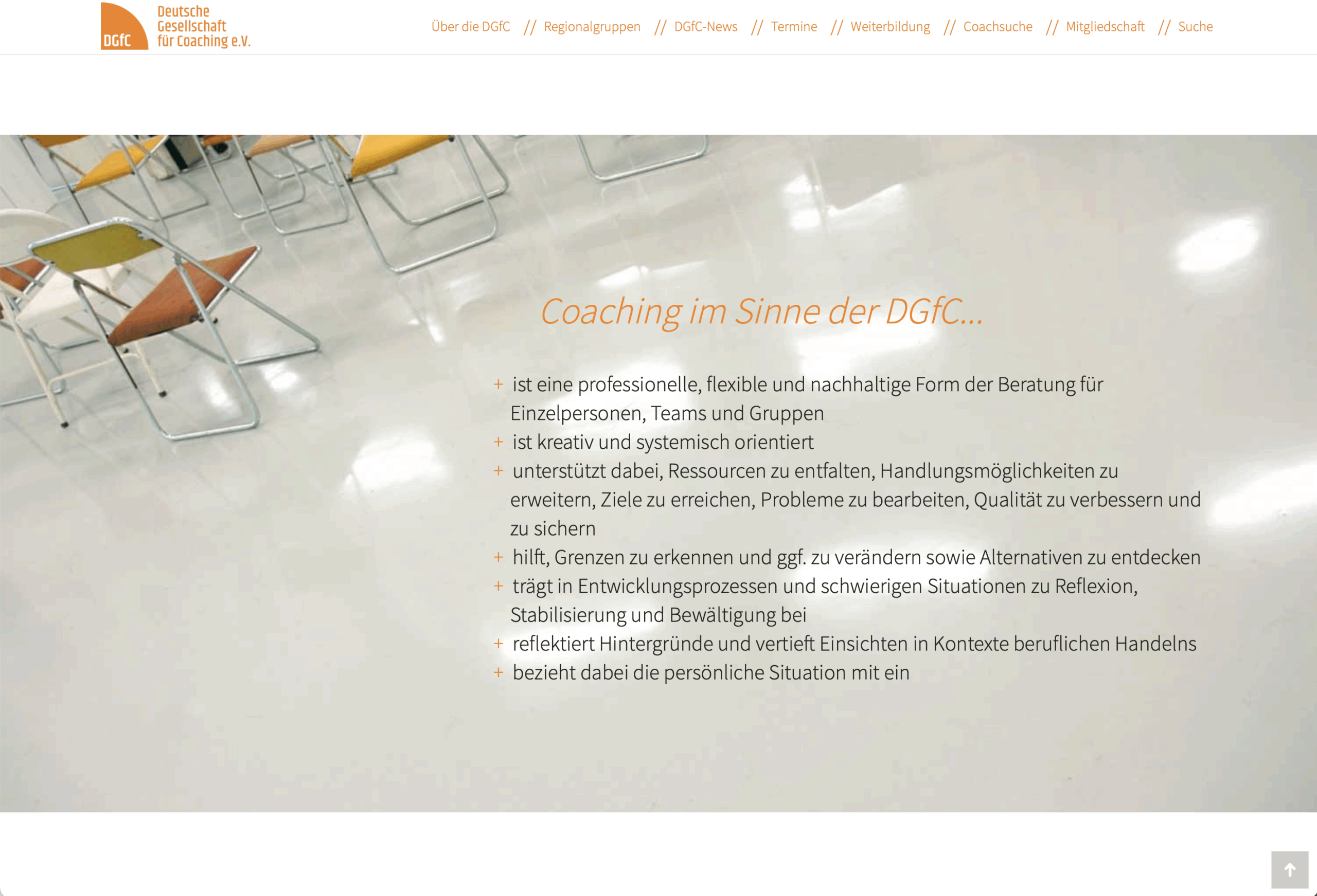 Im Hintergrund sind bunte Stuhlreihen auf einem glänzenden weißen Boden zu sehen, im Vordergrund steht ein deutscher Text, der die Coaching-Grundsätze der DGfC beschreibt. Die Seite hat eine orange-weiße Kopfzeile mit Navigationslinks.